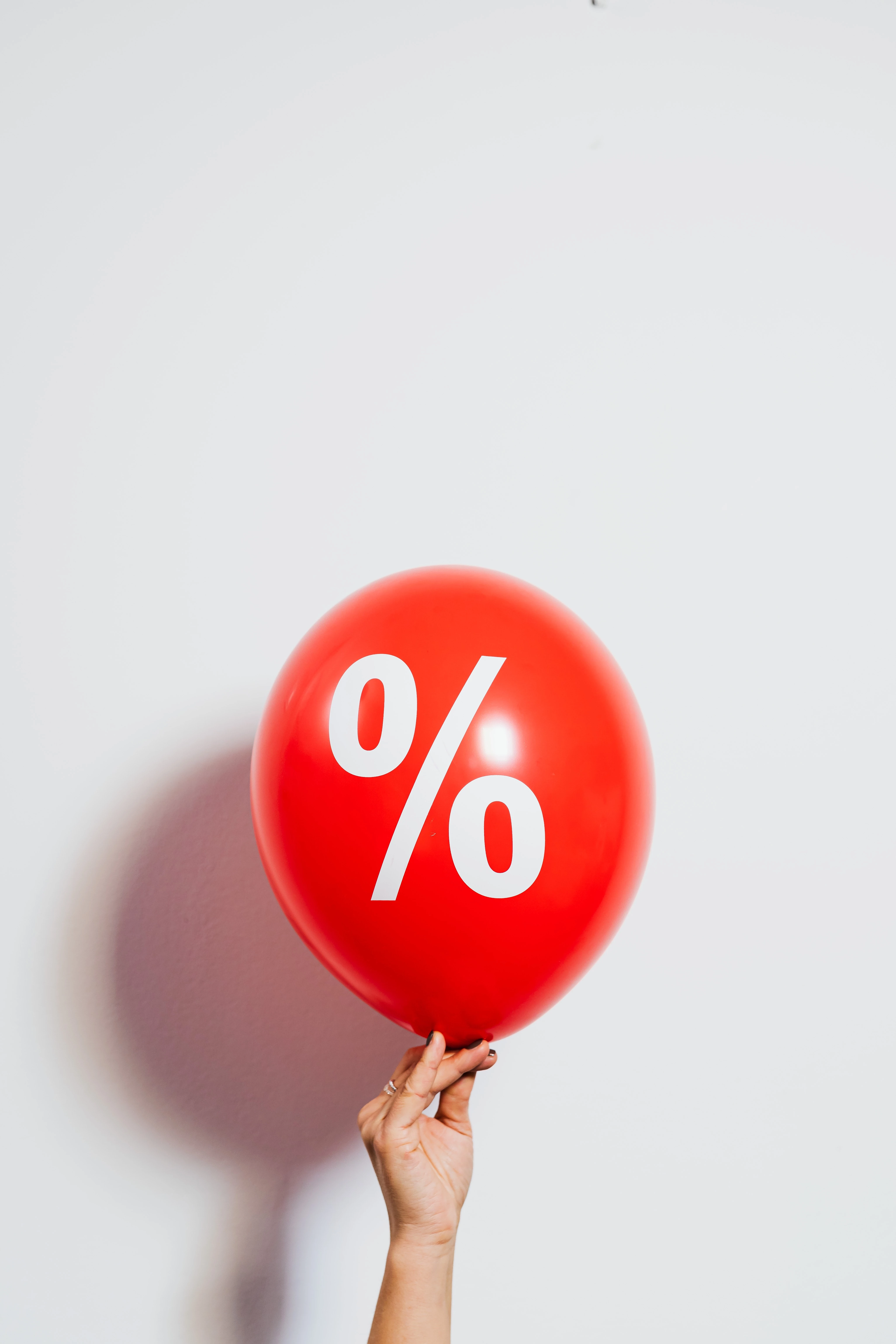 Hand holding big red balloon with % on it