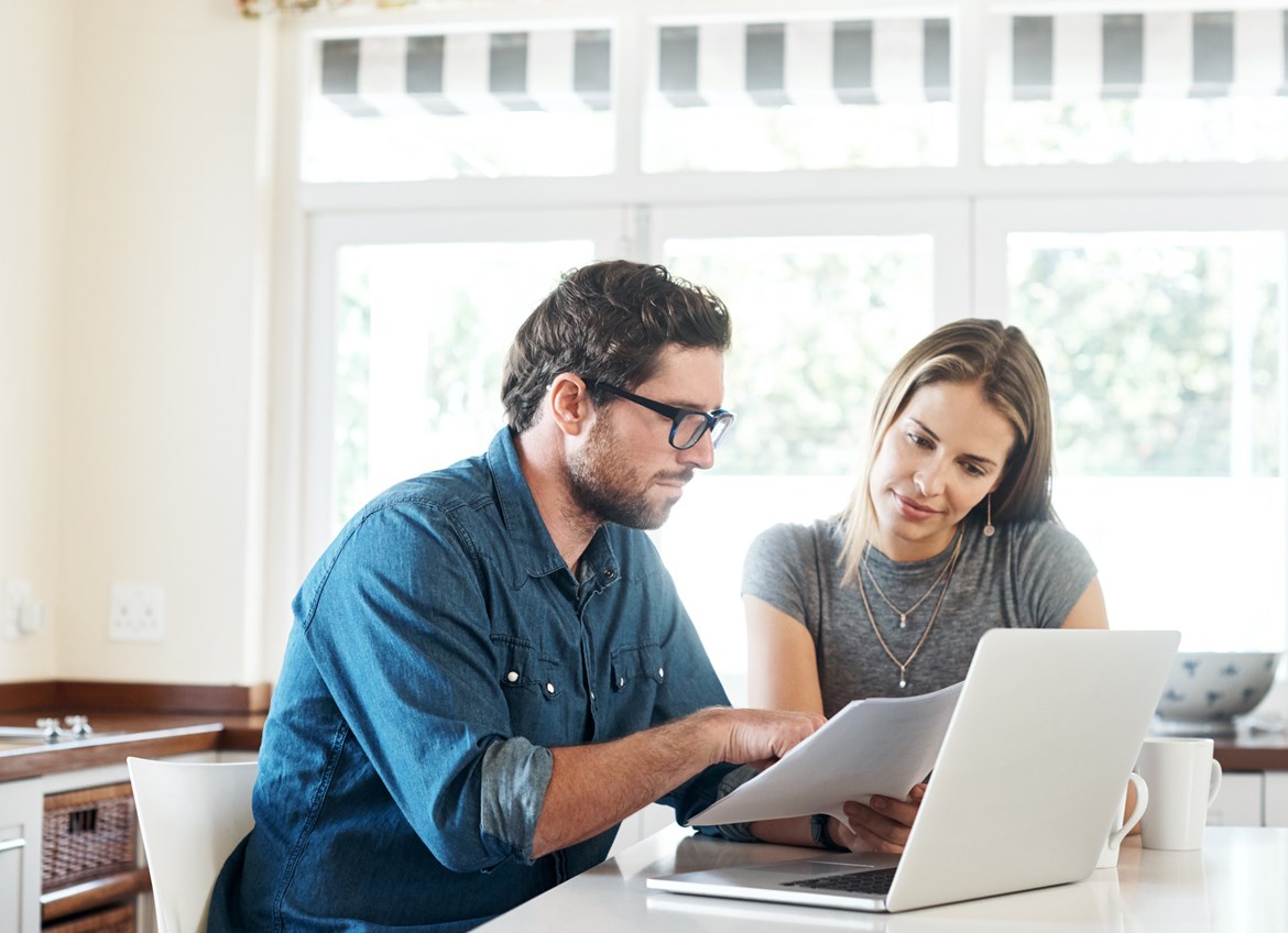 Couple looking at packet of paper over laptop