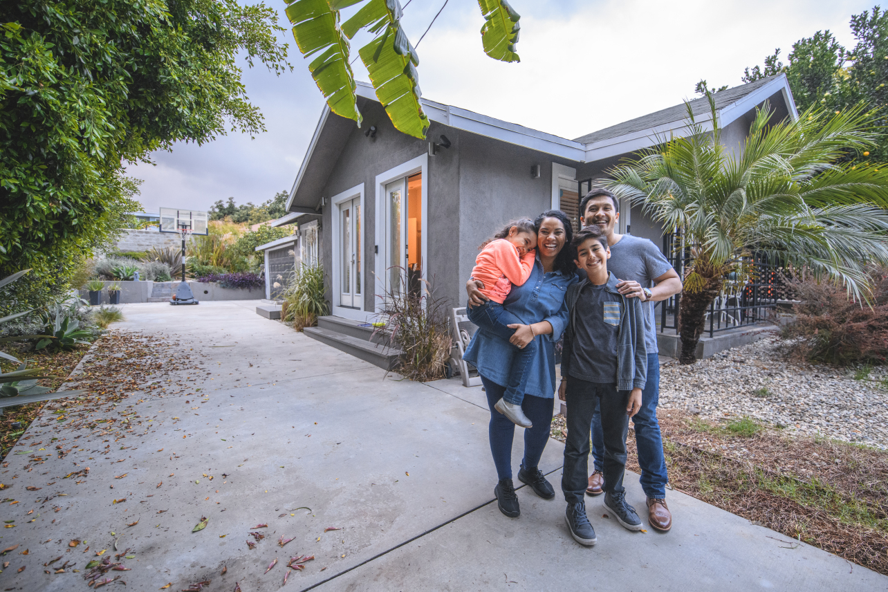 Family smiling in front of their house