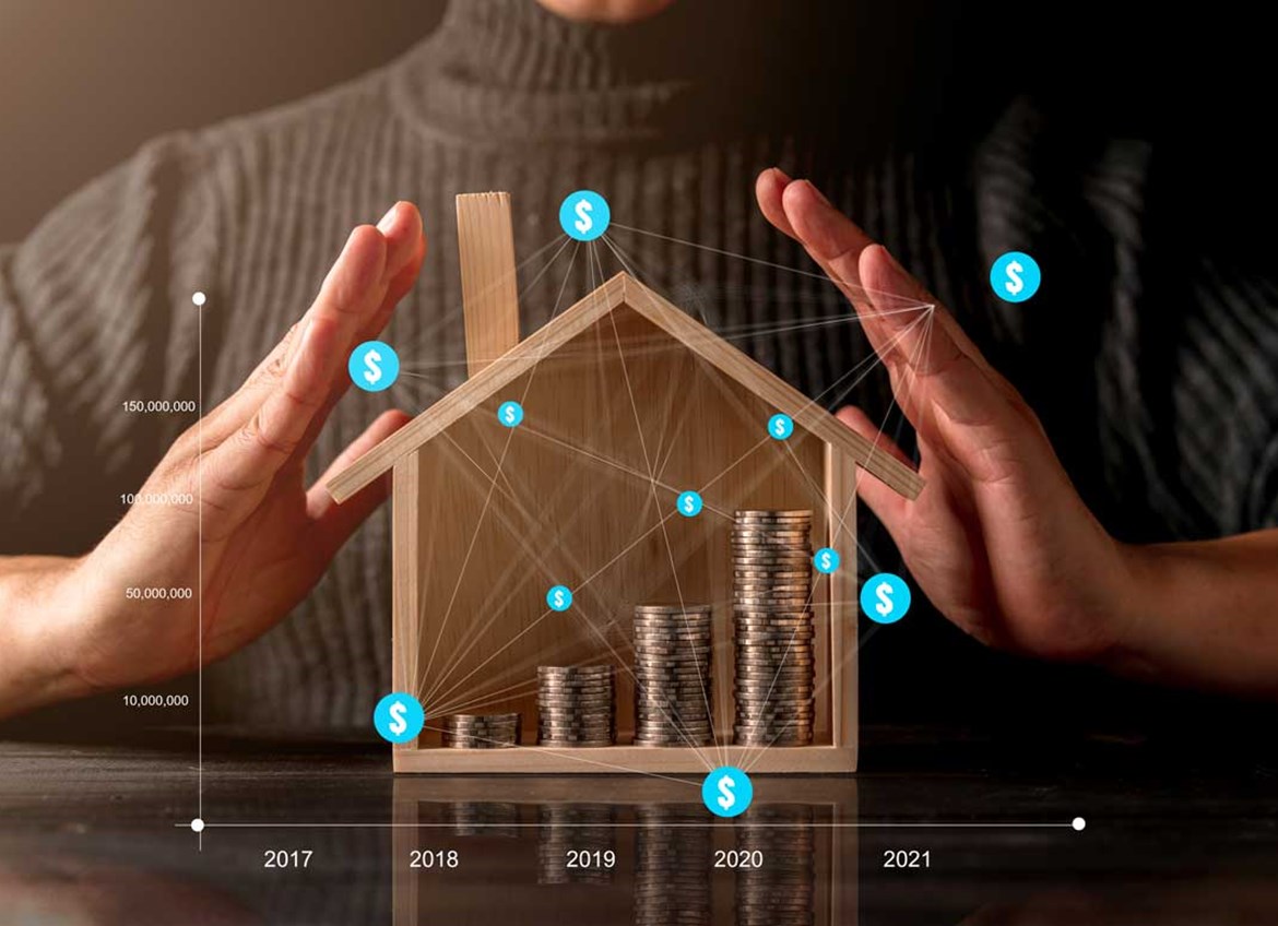 Person putting hands around wooden house with coins inside and graph overlay