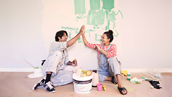 Couple high-fiving while painting a room