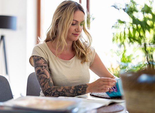 Tattooed woman sitting at a desk working on forms
