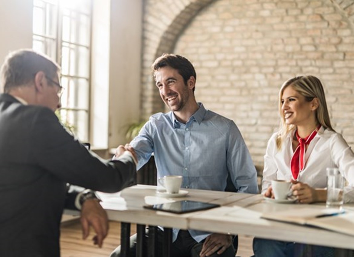 Couple talking to business person while man shakes his hand