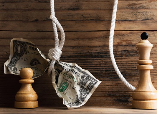 Wooden chessmen and crumpled dollar bill hanging on a tightly knotted white rope