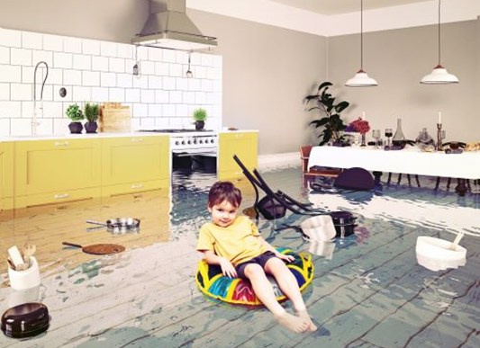 Little boy sitting in inner tube in kitchen full of water
