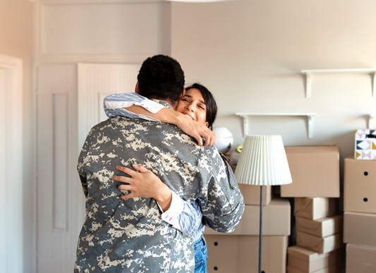 Military couple hugging in front of boxes