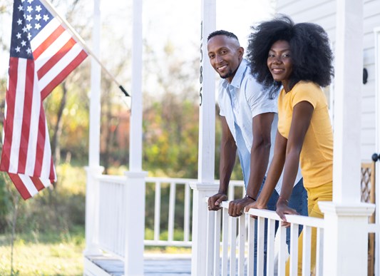 Couple on Front Porch with American Flag in Background