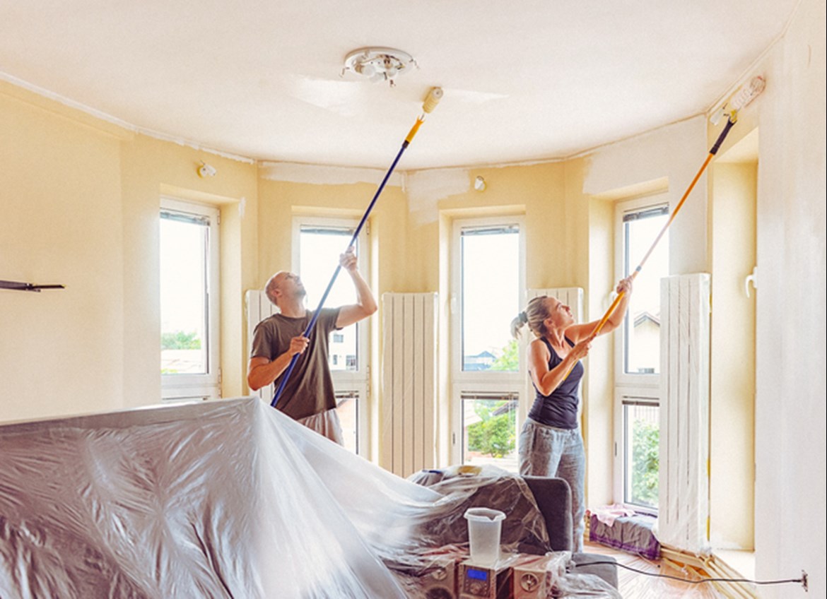 Couple renovating home painting ceiling