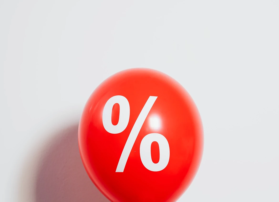 Hand holding big red balloon with % on it