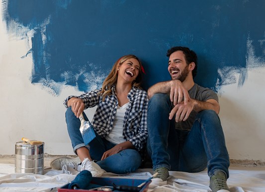 Couple Laughing While Taking a Break from Painting a Room