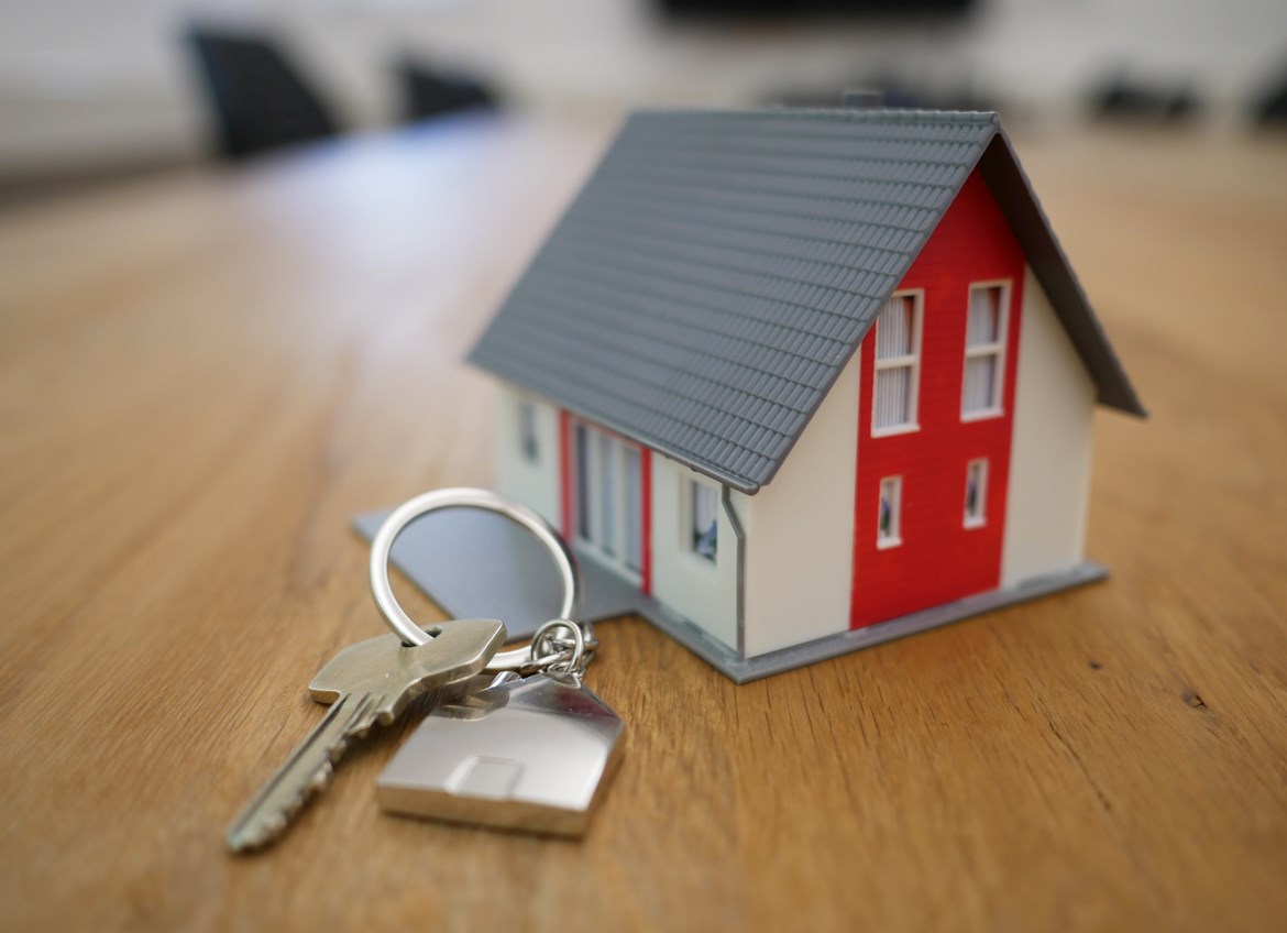 Small house figurine next to key with house keychain